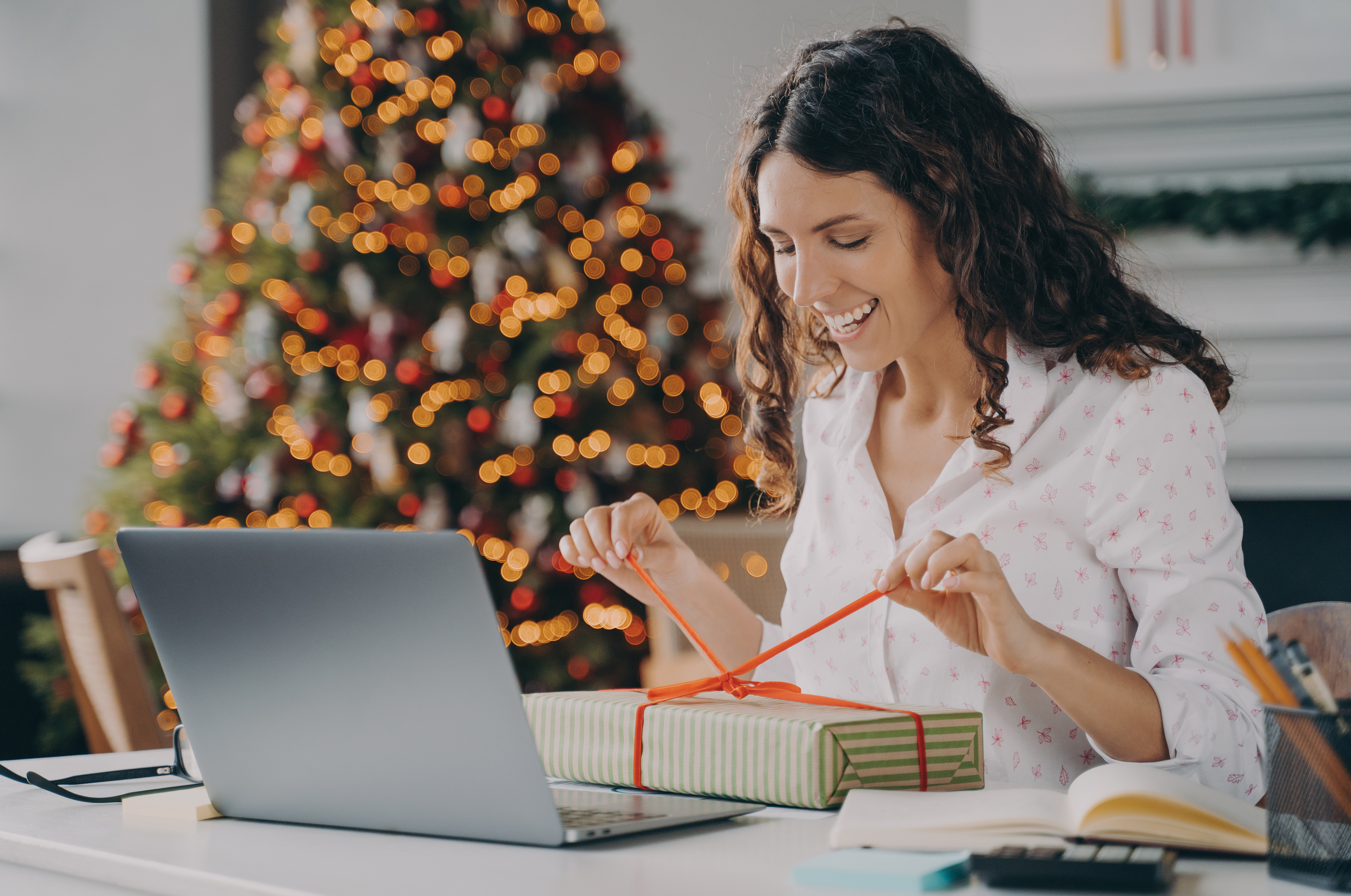 Woman opening a present at her desk at Christmas time