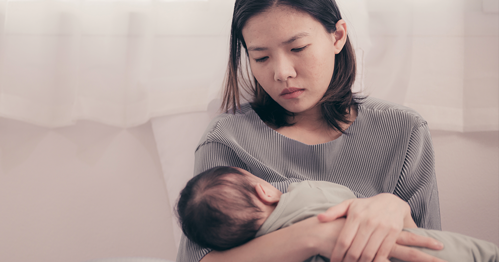 A mother holding a young baby whilst sitting down