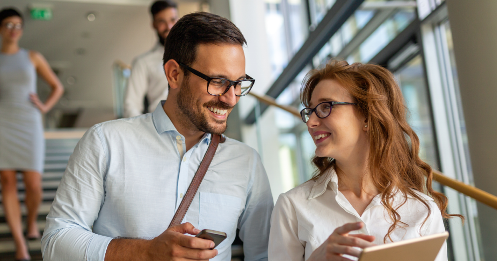 Two co-workers smiling whilst walking down a set of stairs