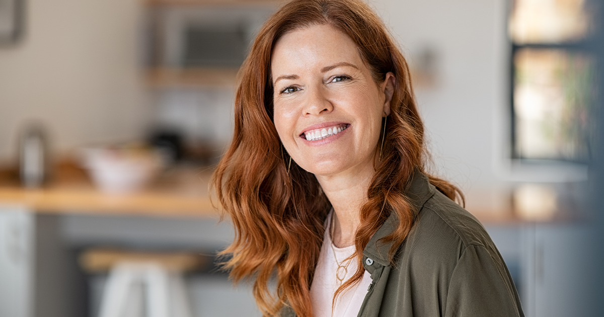 A lady sat in a kitchen smiling