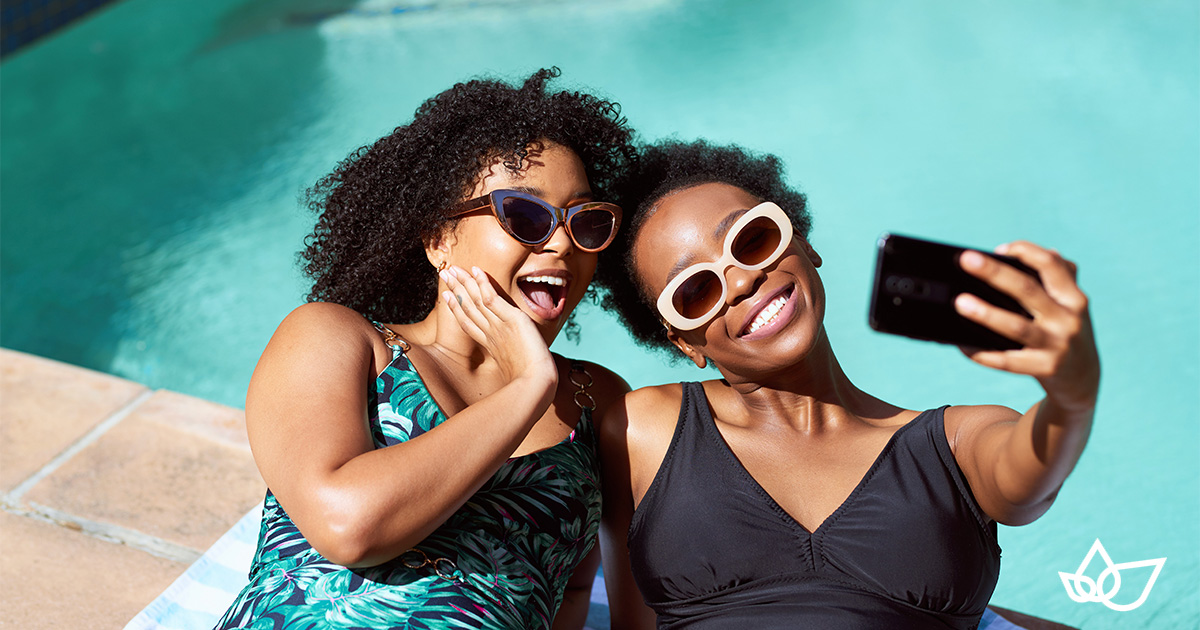 Two women taking a selfie next to a swimming pool