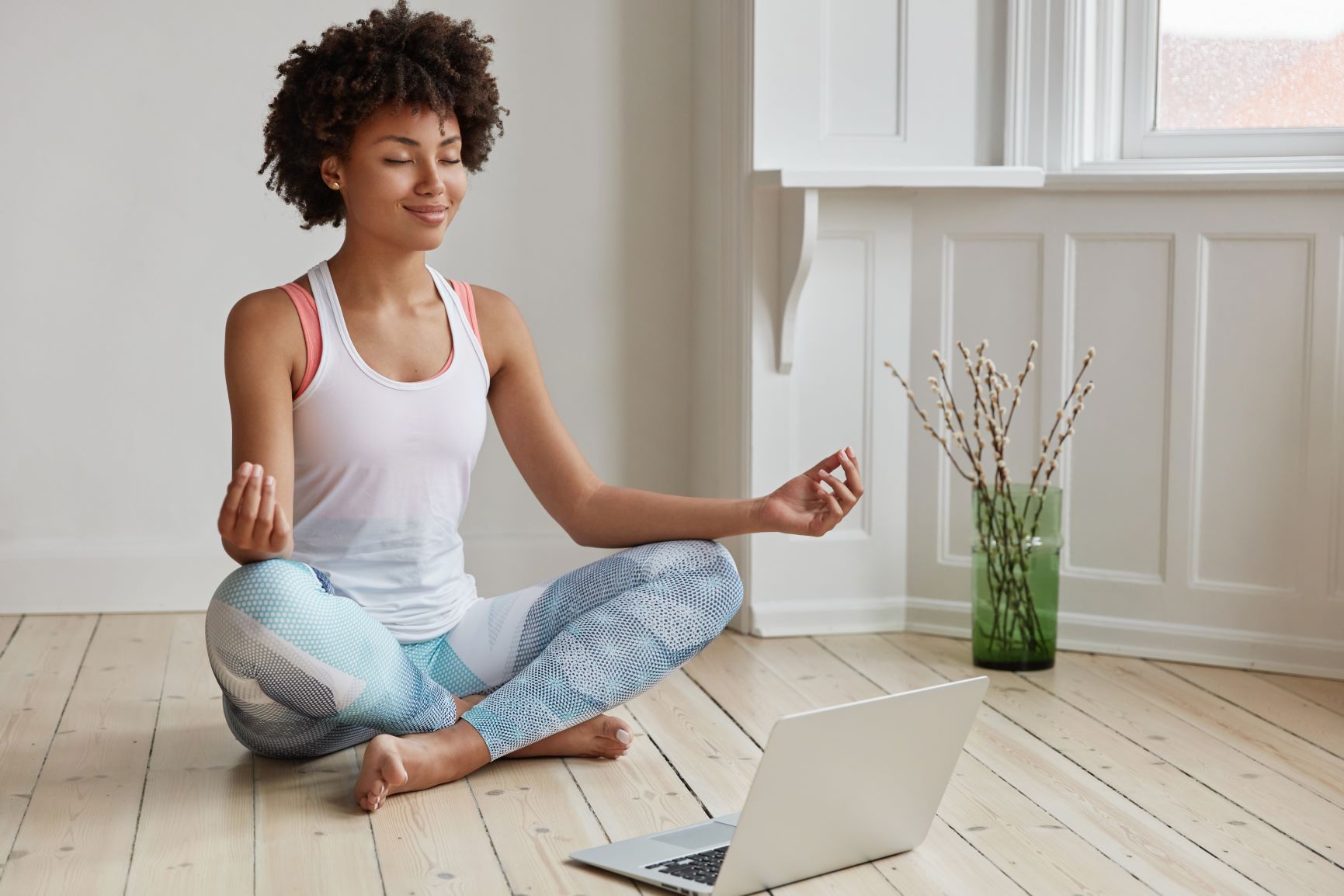 A lady sat meditating in front of her laptop